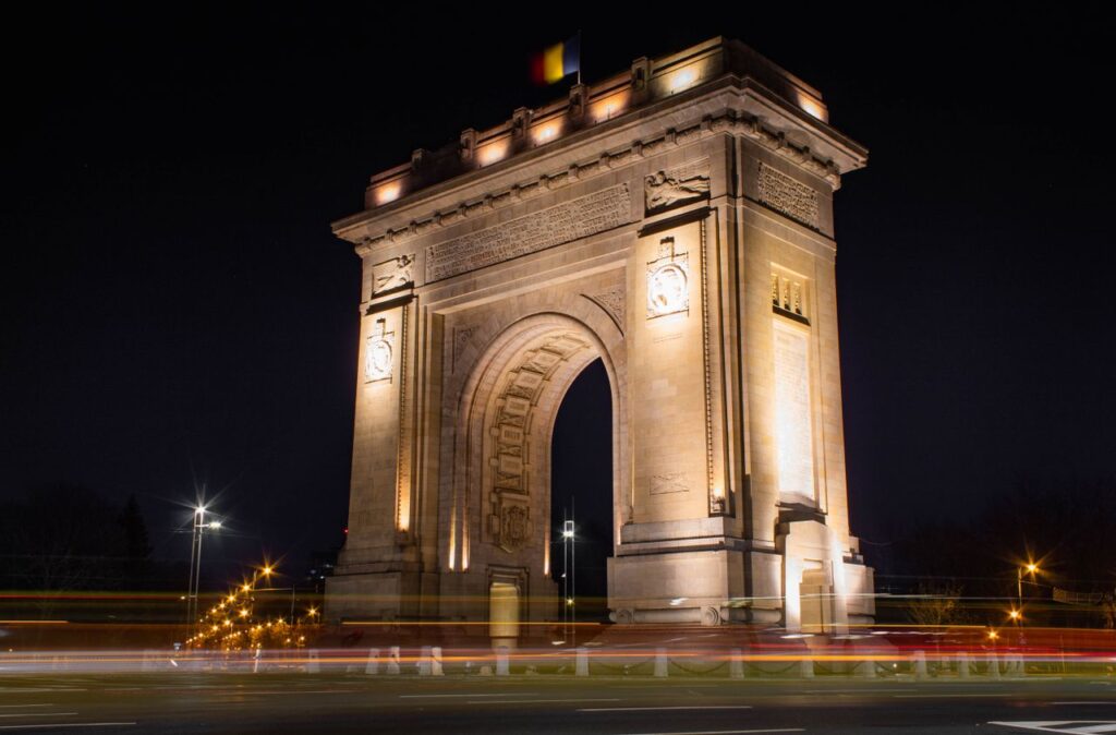 Illuminated Triumphal Arch in Bucharest, Romania, captured at night.